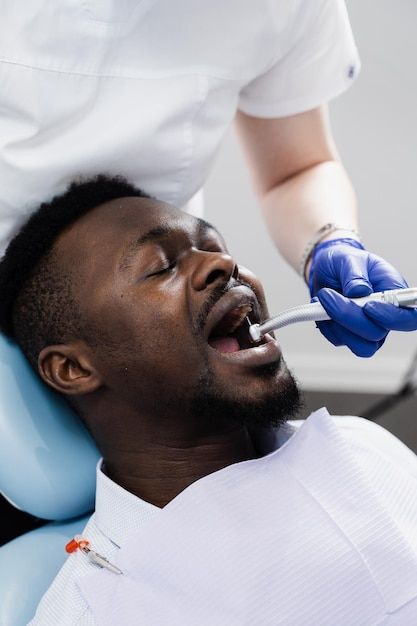 dental drill for african man in dentistry clinic dentist is removing caries and filling teeth for african american patient premium photo